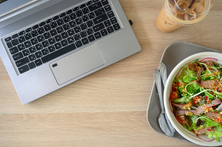 Flat lay, Modern laptop with spicy pork salad and ice coffee on wooden table