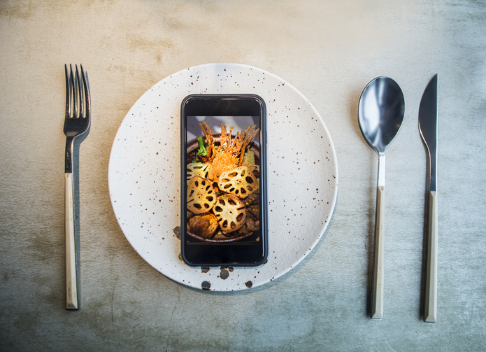 Top view on smartphone with food on screen laying on plate.