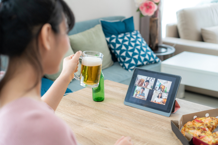 Asian woman virtual happy hour meeting party and drinking alcohol beer online together with her friend in video conference with digital tablet for a online meeting in video call for social distancing for infection risk.