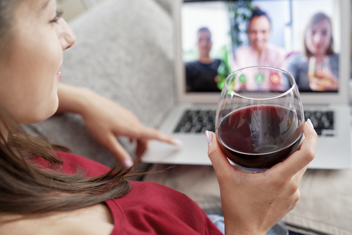 Woman drinking wine during video conference with friends