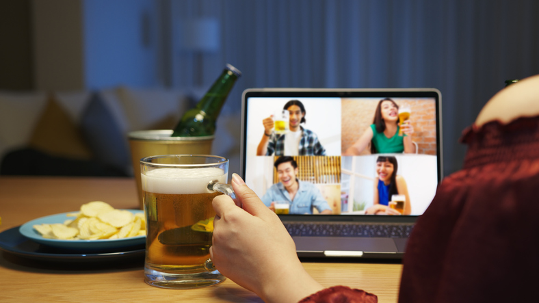 Young happy asian couple enjoy relax night party event online celebration festive with friends at home clinking beer with glass and bottle toasting drinking via video call.