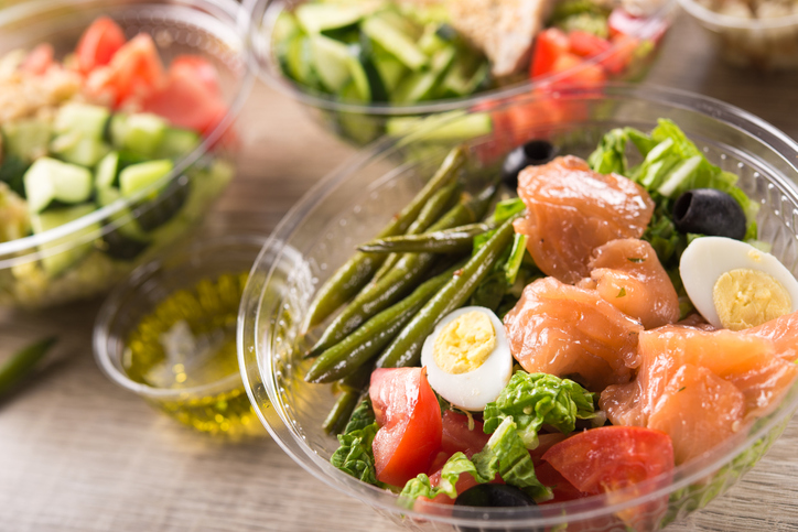 Plastic lunchbox with salmon, egg, tomato, asparagus salad. Healthy lunch food.