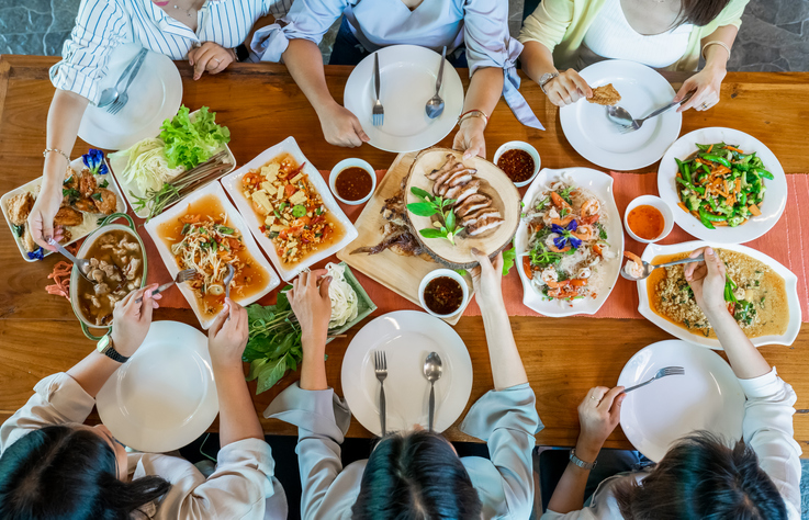 Topview of Thai local food such as Somtum papaya spicy salad, grilled pork, tomyum, vegetable and shrimp curry are arranged on wood table.