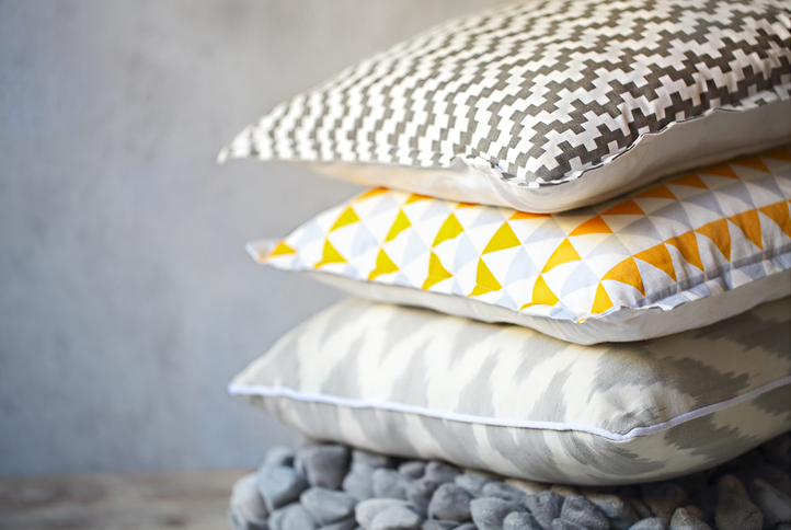 Yellow and grey pillows on the wall background. Close up
