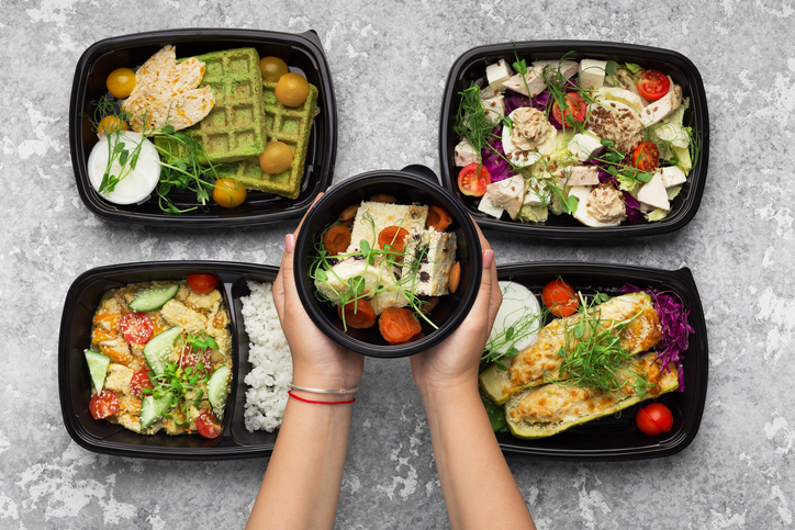 Catering service menu presentation. Woman serving cplastic containers with take away meals, top view